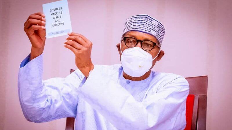 President Buhari Holding a card on safe vaccination